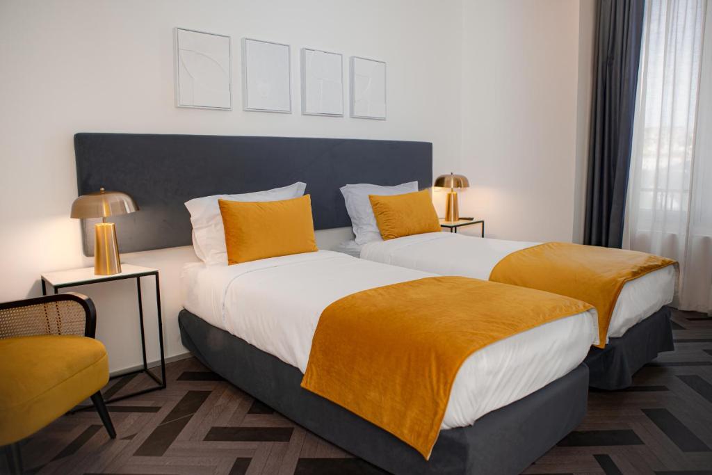 duas camas num quarto de hotel com almofadas amarelas em Glória Suites Hotel em Lisboa