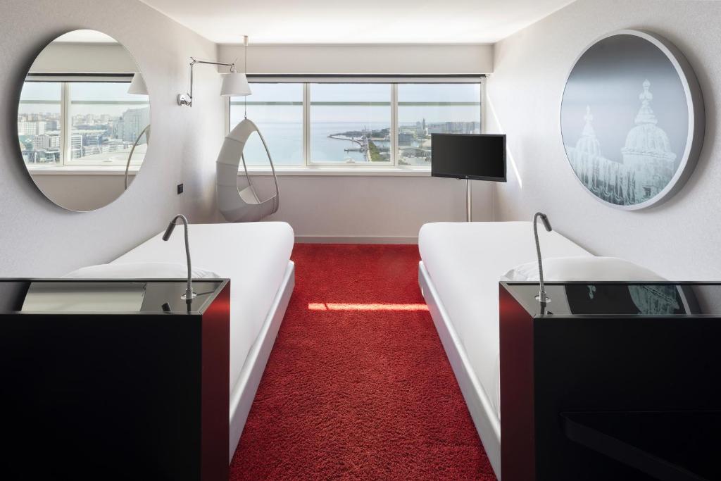 A twin-bed room with waterfront windows, red carpet and matching black bedside furniture.