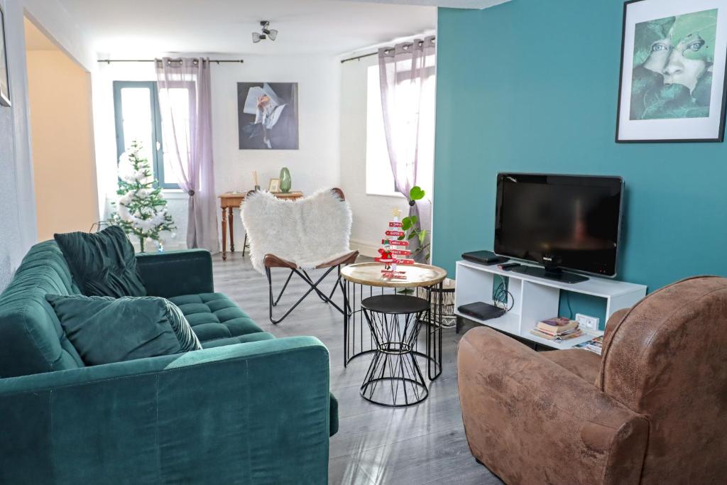 - un salon avec un canapé vert et une télévision dans l'établissement Les Gîtes de Laure - L'Or Vert, Appartement avec Vue sur le Château, Parking Privé, Climatisation, Netflix, à 160 m de la Cité Médiévale, à Carcassonne