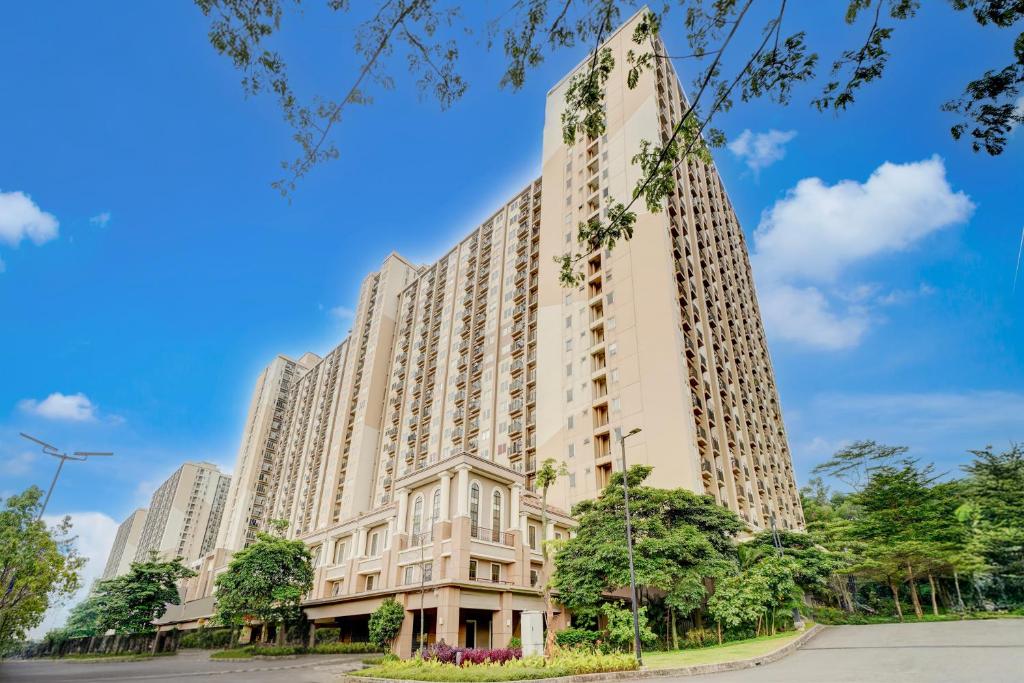 un grand bâtiment blanc avec des arbres devant lui dans l'établissement OYO 94838 Dahoma Tower, à Tjikuda Tiga