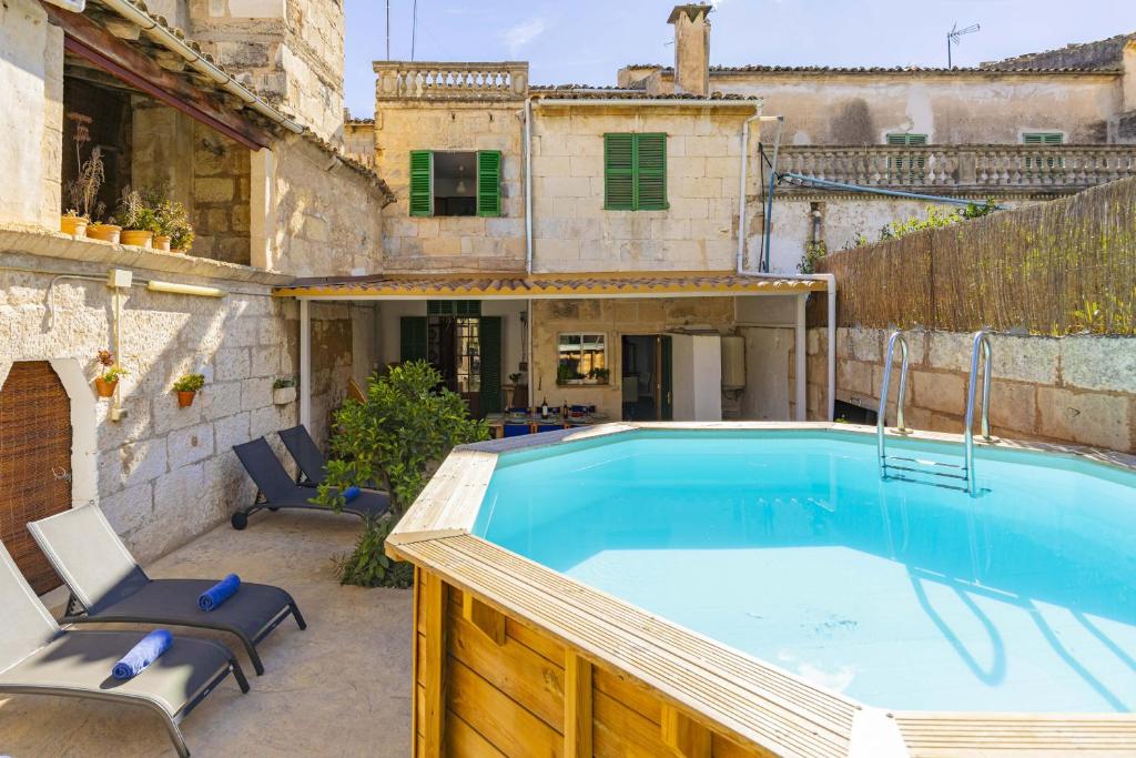 - une piscine avec 2 chaises à côté d'un bâtiment dans l'établissement Casa de Can Virolla Gran, à Sa Pobla