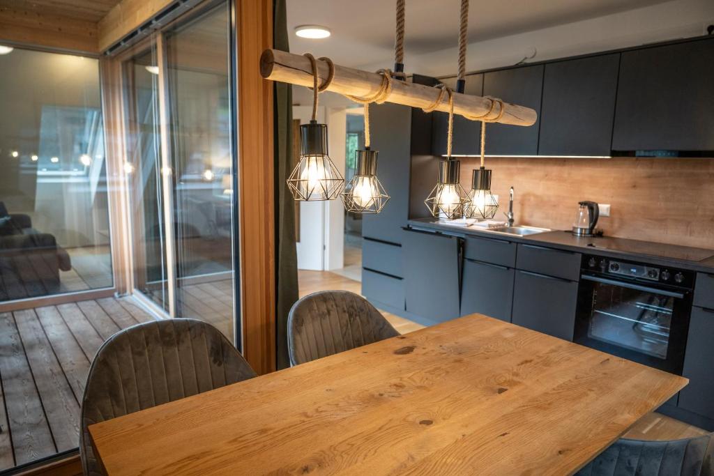 Una cocina con una mesa de madera y algunas sillas. en Dorfplatzl Suite, en Hohentauern