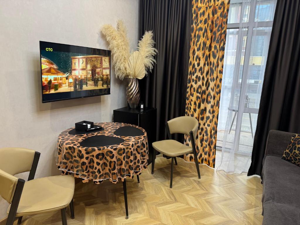 a living room with a table and chairs and a tv at Байсанат 2 in Karagandy