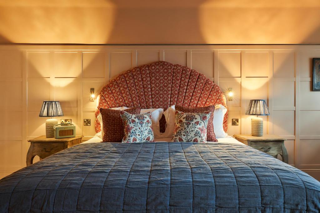 um quarto com uma cama grande com uma cabeceira grande em The Potters Heron - A Heartwood Inn em Romsey