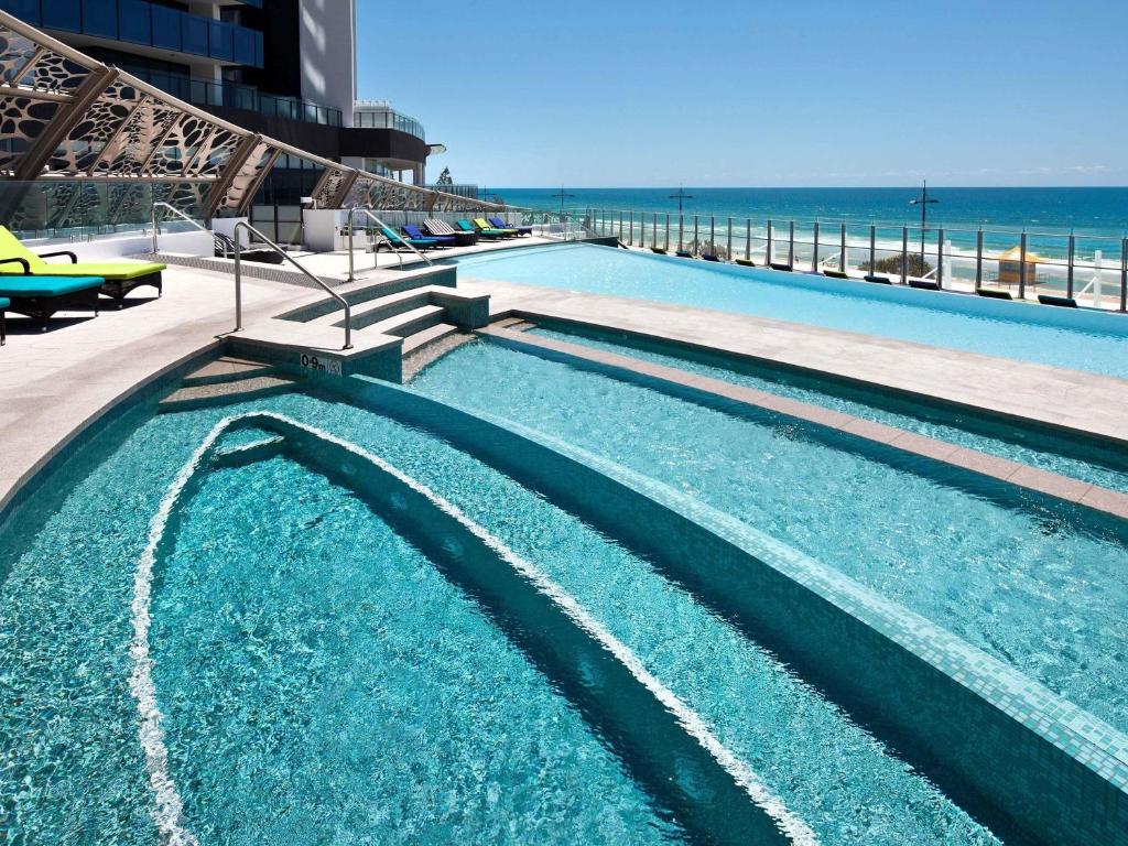a large swimming pool with the ocean in the background at Peppers Soul Surfers Paradise in Gold Coast