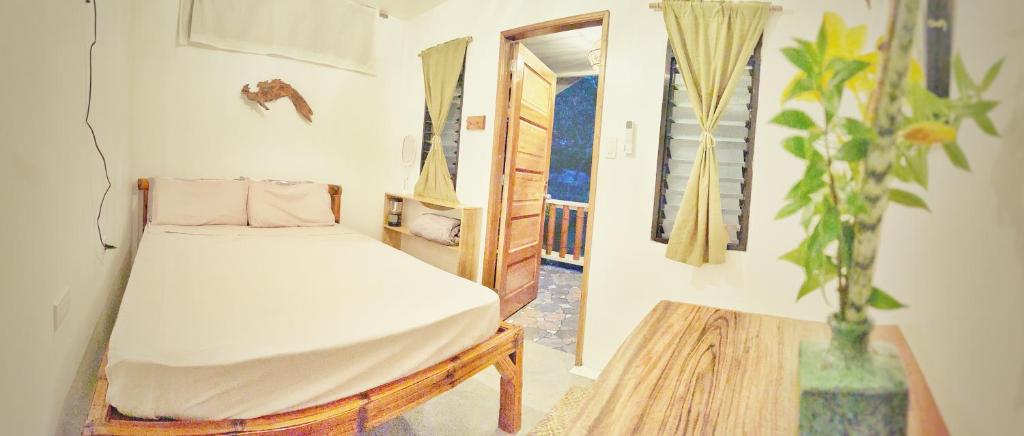 a small bedroom with a bed and a table at The Village Eco-Bungalows in Salvacion, Busuanga in Busuanga