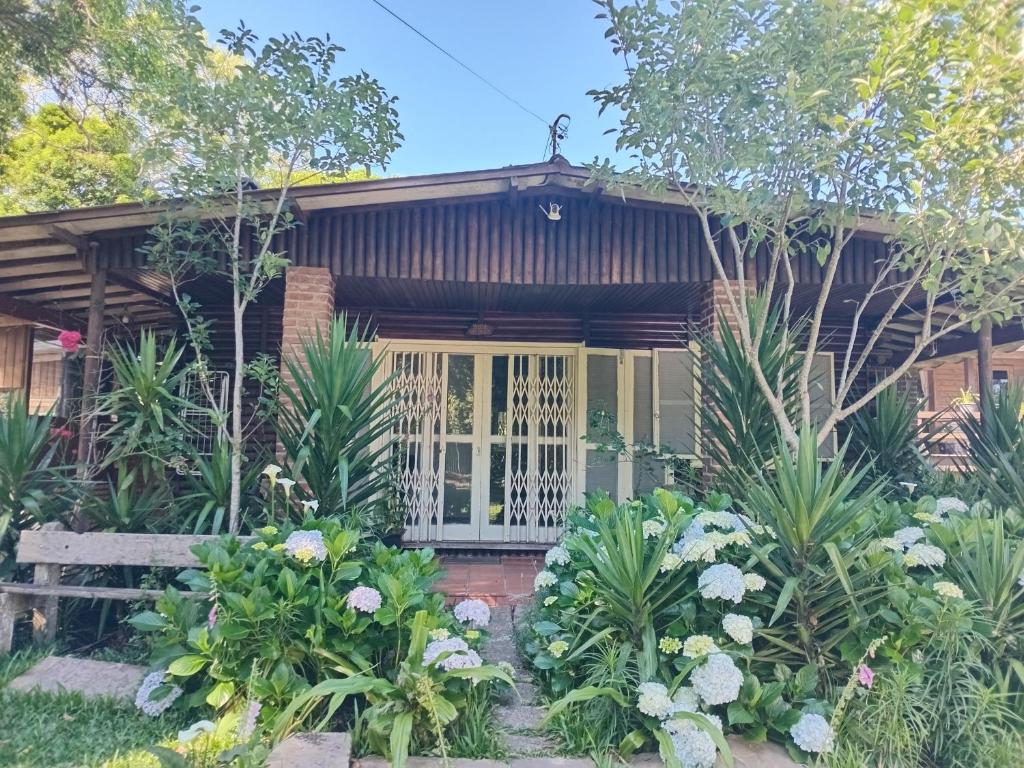 uma casa com um alpendre e algumas plantas em Chalé alpino em canela rs todo mobiliado com cozinha lareira split Wi-Fi 2 quartos perto do centro em Canela