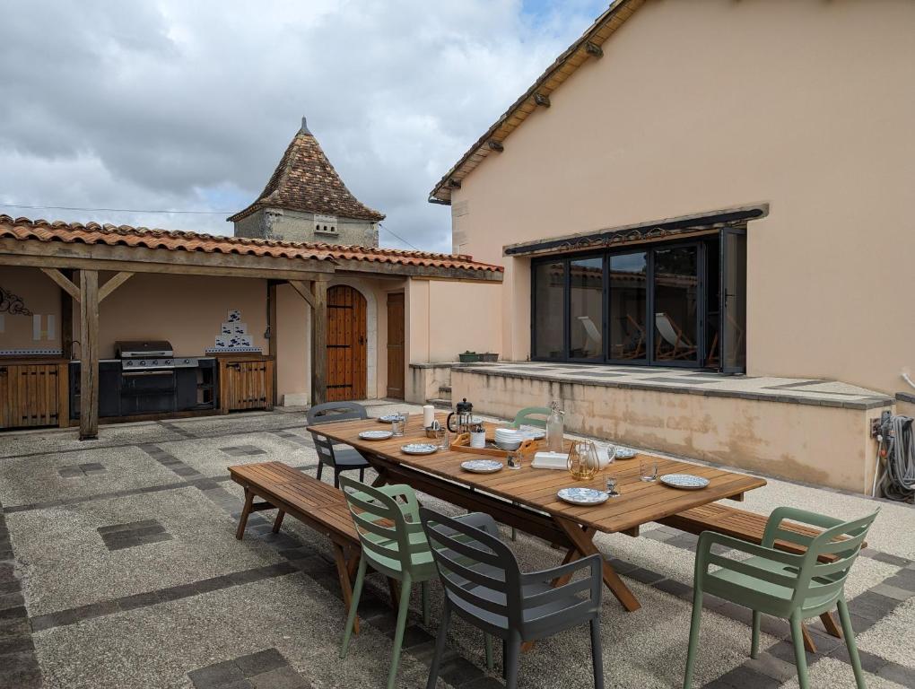 a wooden table and chairs on a patio at Grange des Bardins in Villebois-Lavalette
