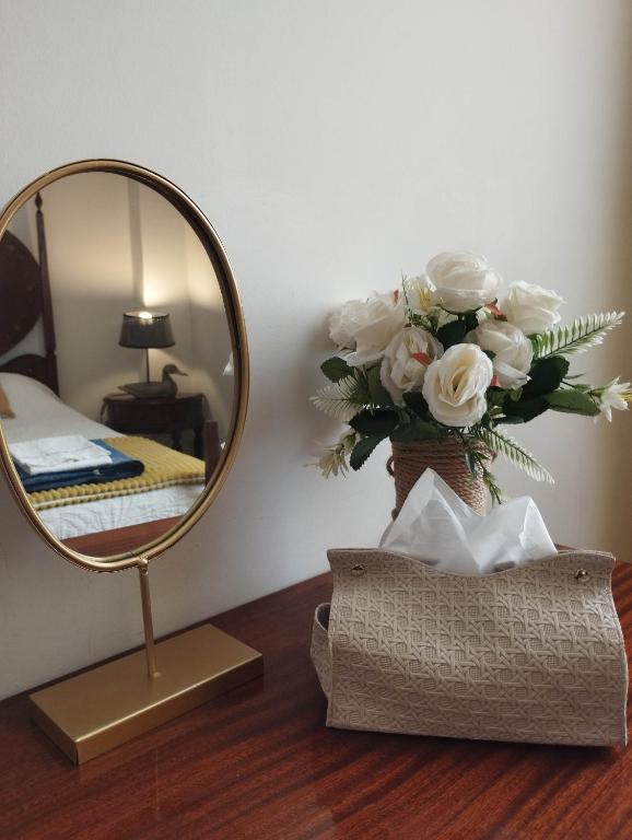 a mirror on a table next to a vase of flowers at Blue Castle House in Gouveia