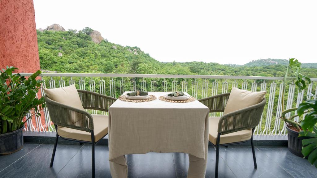 a white table and chairs on a balcony at VSR Vriksha Naturopathy Wellness Resort in Hyderabad