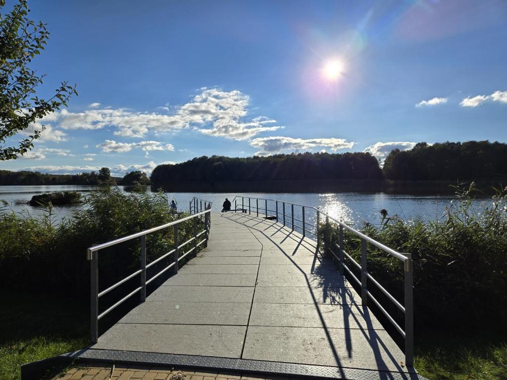 a walkway over a lake with a person on it at Apartmenthaus-Usedom Kajüte 7 in Kolpinsee