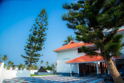 a house with an orange roof and a pine tree at Ocean Queen Palace Kovalam in Trivandrum