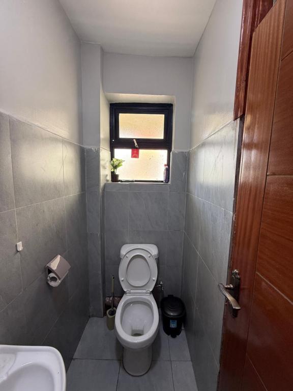 Un pequeño baño con inodoro y ventana. en Solara Loft, en Nairobi
