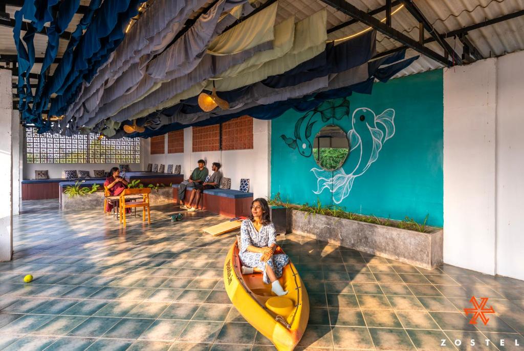 una mujer sentada en un kayak en un restaurante en Zostel Alleppey, en Alleppey