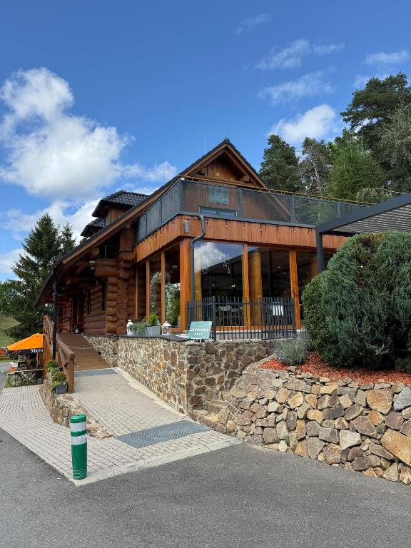 a large log cabin with a stone wall at Chata Lada Repechy in Bousín