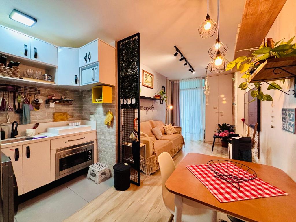 a kitchen and living room with a table and a couch at Ap completo com ar e garagem coberta próximo ao metrô in Brasília