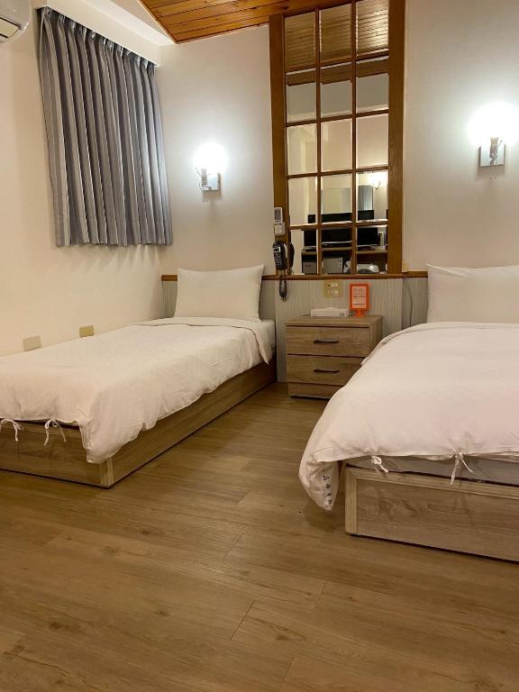 a bedroom with two beds and a mirror at Traveler Hotel Taitung in Taitung City
