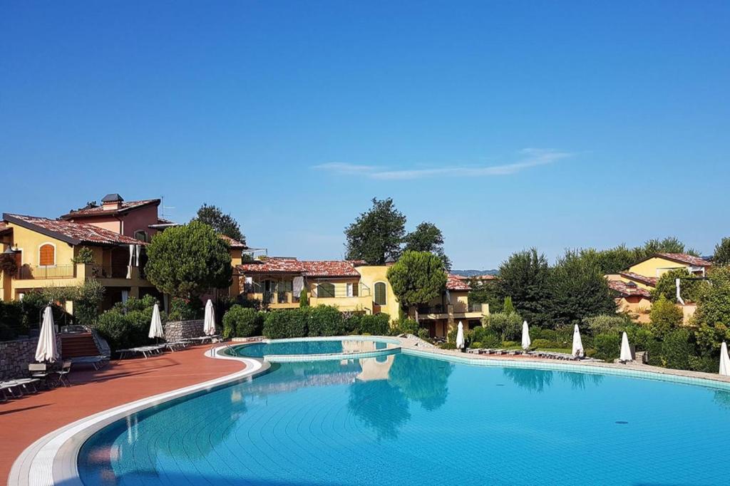 a large swimming pool with chairs and umbrellas at Borgo del Torchio H3 ByBookinggardalake in Manerba del Garda