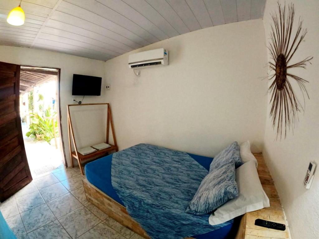 een slaapkamer met een blauw bed en een ventilator bij Pousada da Vivi in Maracaipe