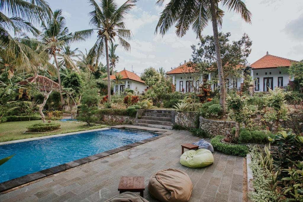a villa with a swimming pool in front of a house at De Casa Ananda Nusa Penida in Nusa Penida