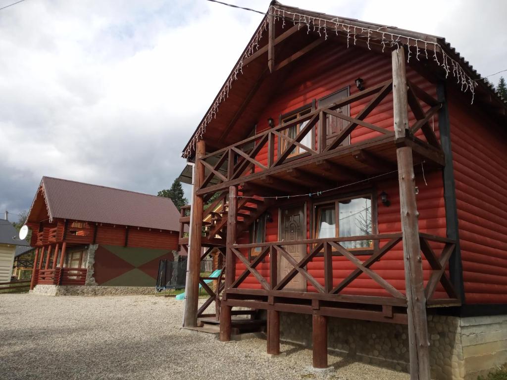 eine Blockhütte mit einem roten Haus in der Unterkunft Котедж Арніка in Worochta