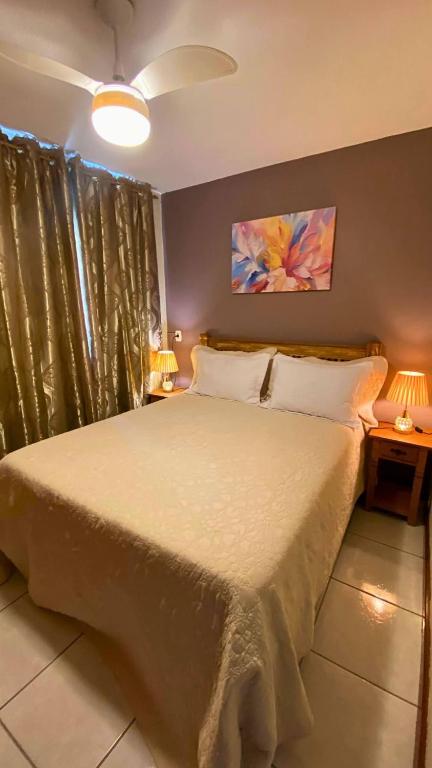 a bedroom with a large bed with two lamps at Excelente Apartamento Climatizado em Jacaraipe in Serra