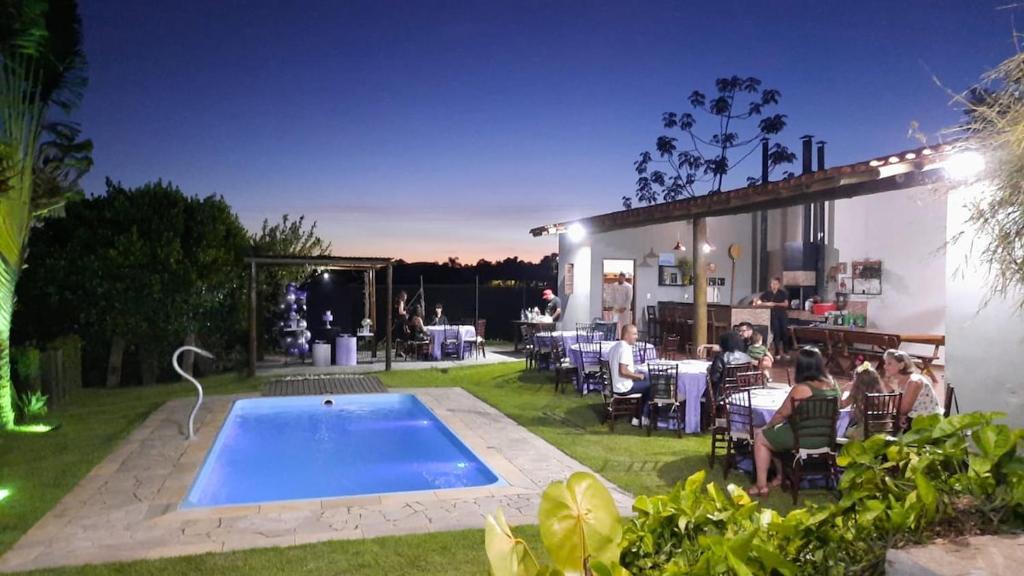 - une piscine dans une cour avec des personnes assises autour dans l'établissement Rancho São Miguel Arcanjo, à Caçapava