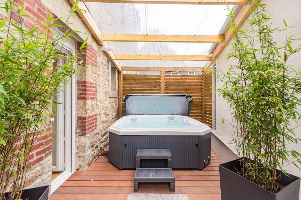 a hot tub on a patio with plants at Charmant Duplex avec jacuzzi Guingamp centre in Guingamp