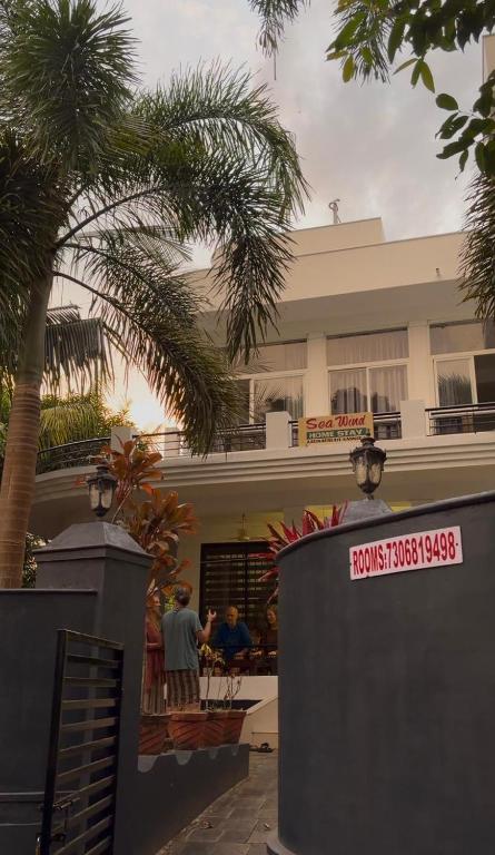 two people standing in front of a building with palm trees at Seawind in Kannur