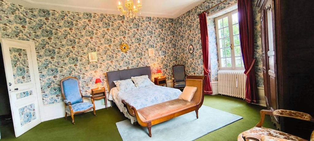 a bedroom with a bed and two blue chairs at Demeure 13 Personnes Au Centre Ville De Ruffec in Ruffec