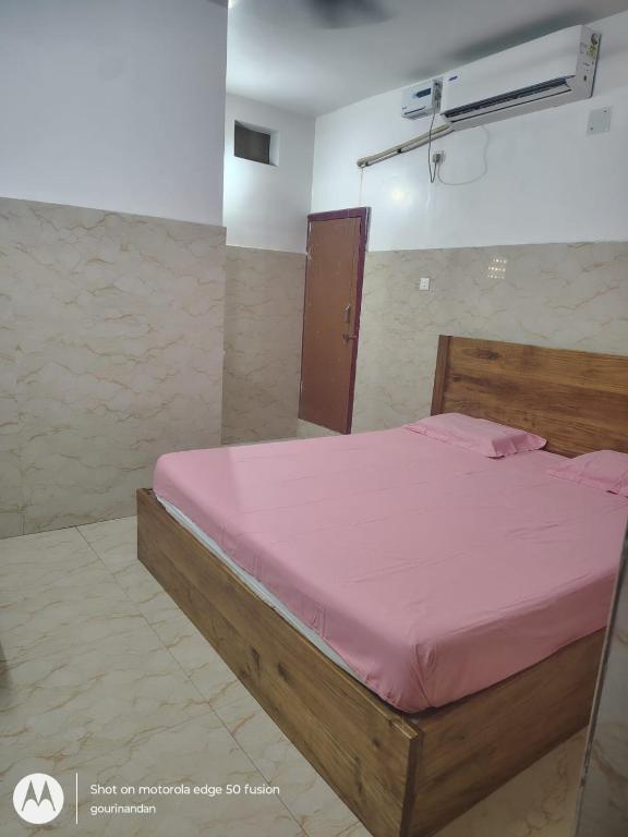 a bedroom with a wooden bed with a pink sheets at Gourinandan lodge 300m from sea beach 1km from railway station in Puri