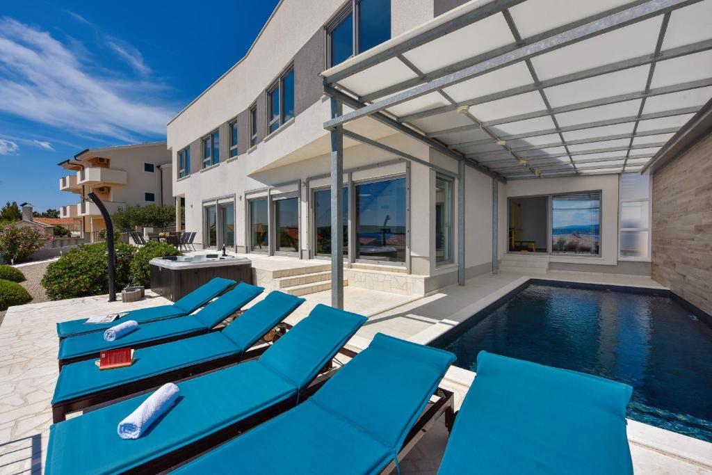 una piscina con sedie a sdraio blu accanto a una casa di Villa Costabella with heated pool a Posedarje (Possedaria)