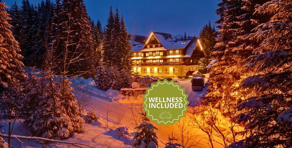 un gran edificio con un cartel en la nieve en Hotel Mikulášska Chata, en Demänovská Dolina