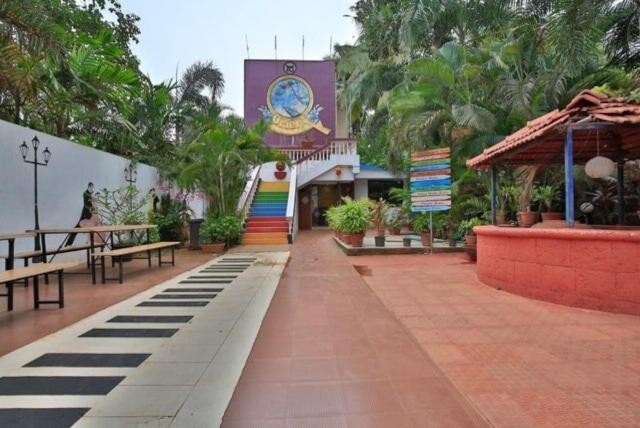 ein Innenhof mit Bänken und ein Gebäude mit einer Uhr in der Unterkunft Hotel Orient Royal in Calangute