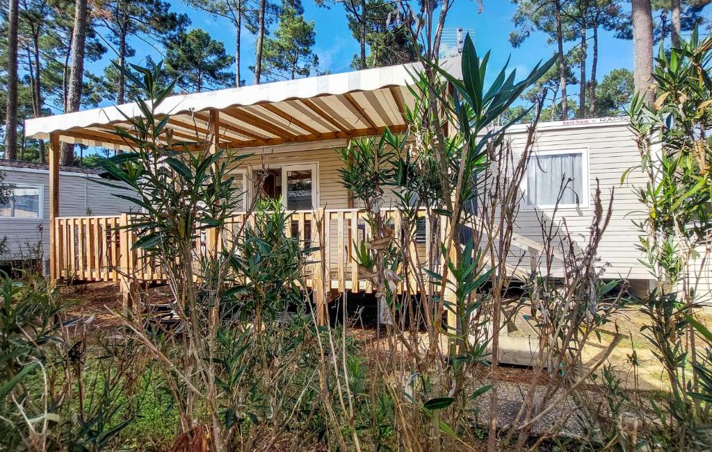 a small yellow house with a wooden porch at Nice Stacaravan In Saint-Julien-En-Born in Saint-Julien-en-Born
