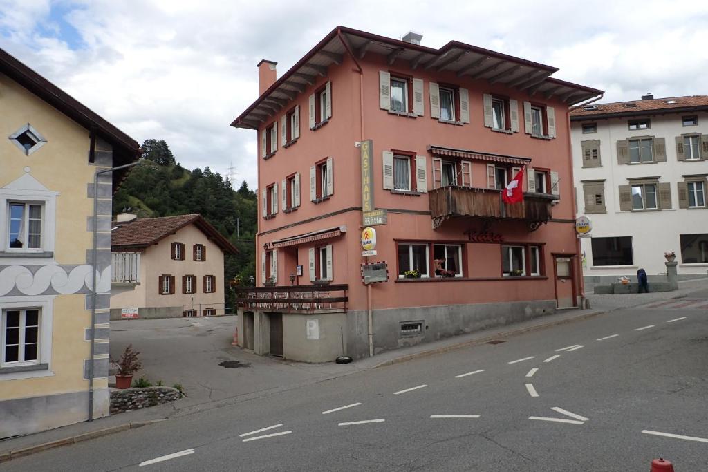un bâtiment rose sur le côté d'une rue dans l'établissement Hotel Rätia, à Tiefencastel
