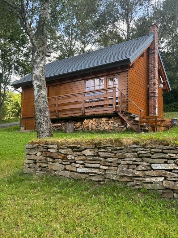 a log cabin with a stone wall and a tree at Roubenka in Železná Ruda