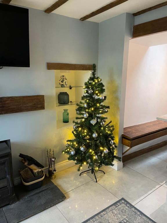 a christmas tree in a living room with a fireplace at Brock cottage Tideswell newly modernised in heart of Peak District National Park in Tideswell