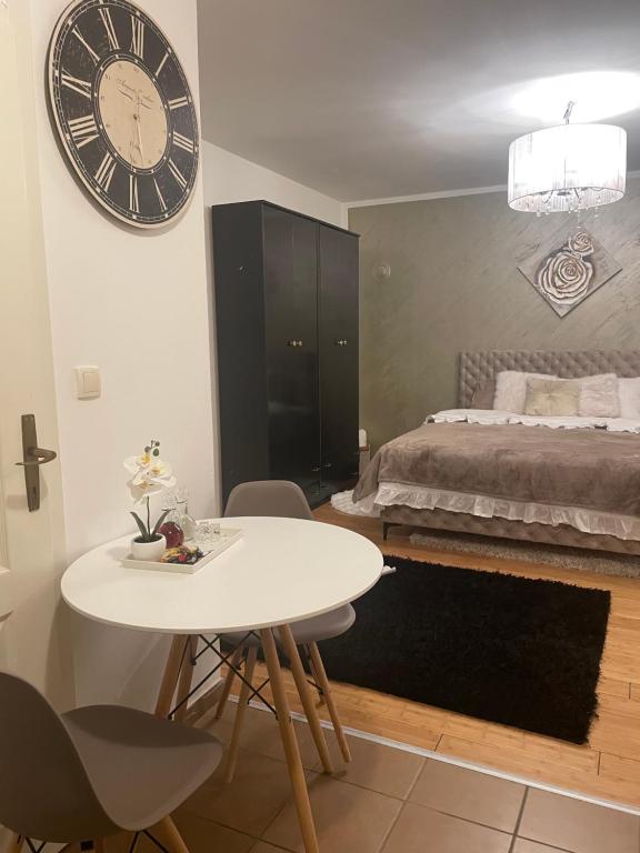 a bedroom with a white table and a large clock on the wall at Roza in Ruma
