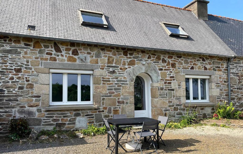 Trézény2 Bedroom Beautiful Home In Rospez的石头建筑外的桌椅