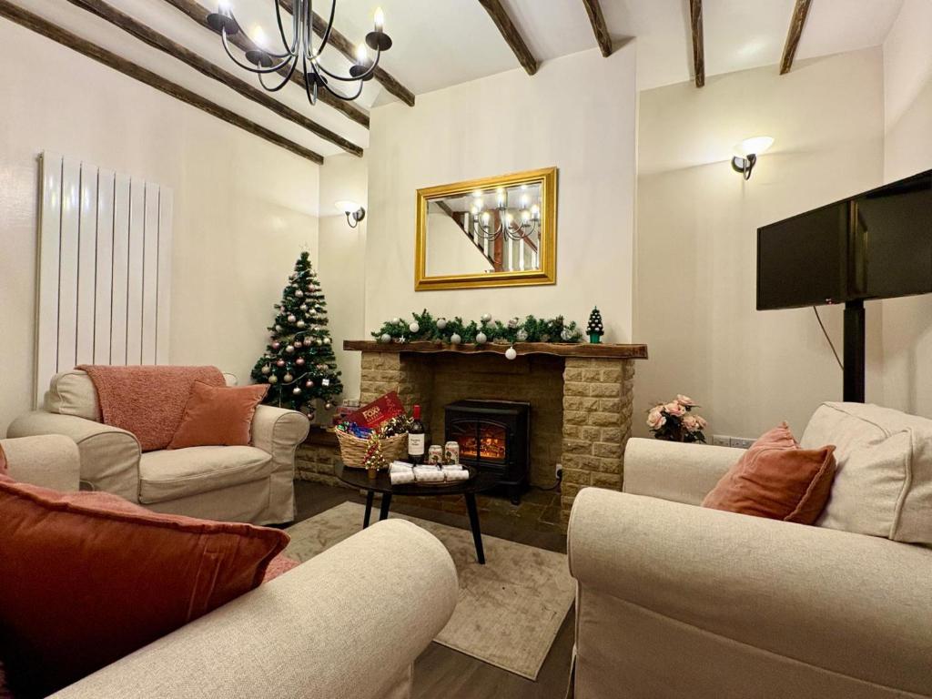 un salon avec une cheminée et un arbre de Noël dans l'établissement Central Buxton - Modern Cottage - Peak District, à Buxton