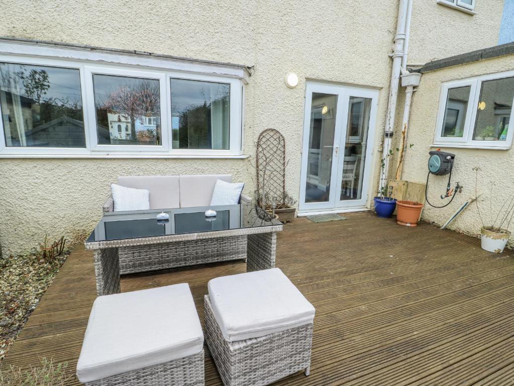 a patio with two white chairs and a grill at Hafan Hapus in Beaumaris
