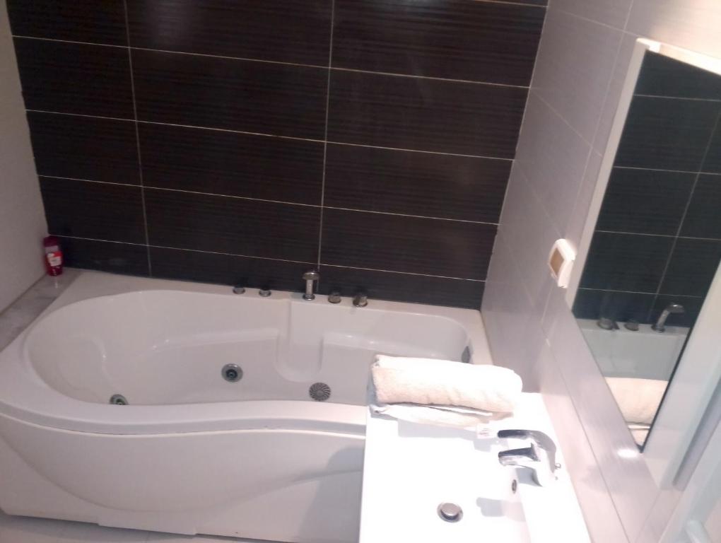 a bathroom with a white bath tub and a sink at Appartement les jardins de Carthage in Carthage