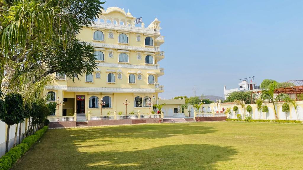 um grande edifício amarelo com um gramado na frente em Umrao Mahal - A Boutique Heritage Hotel & Resort Jaipur em Jaipur