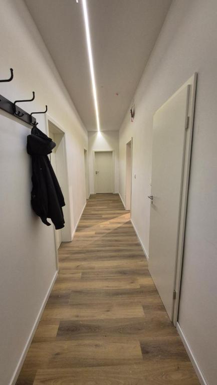Wohnung zentral zwischen Gladbeck und Buer في غلادبك: ممر مع ممر طويل مع جدران بيضاء وأرضيات خشبية