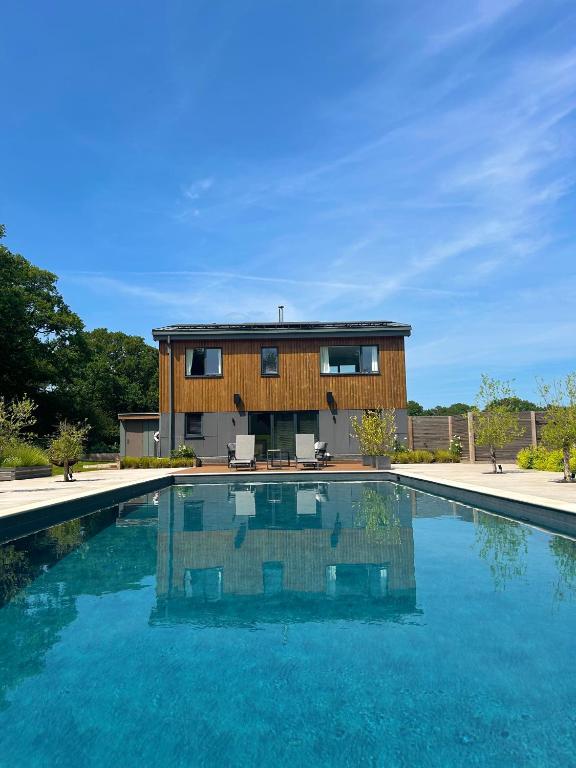 a house with a swimming pool in front of a house at Large Heated Pool with Countryside Views in Cowfold