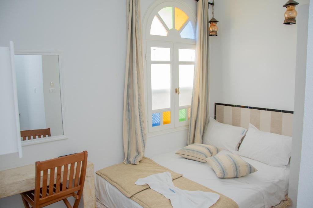 马赫迪耶Hôtel Al Jazira Mahdia的一间卧室配有一张带窗户和椅子的床