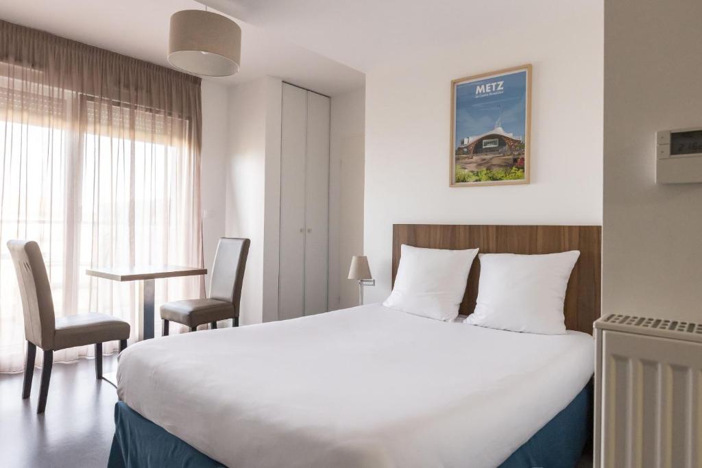 a hotel room with a large bed and two chairs at Appart Hotel Odalys City Metz Manufacture in Metz