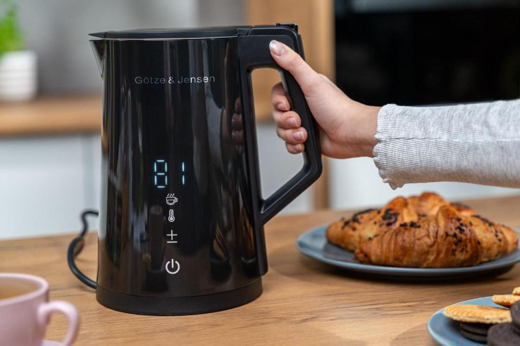 a hand is holding a black coffee pot on a table at Lust&Desire BDSM Krakow Apartment in Kraków