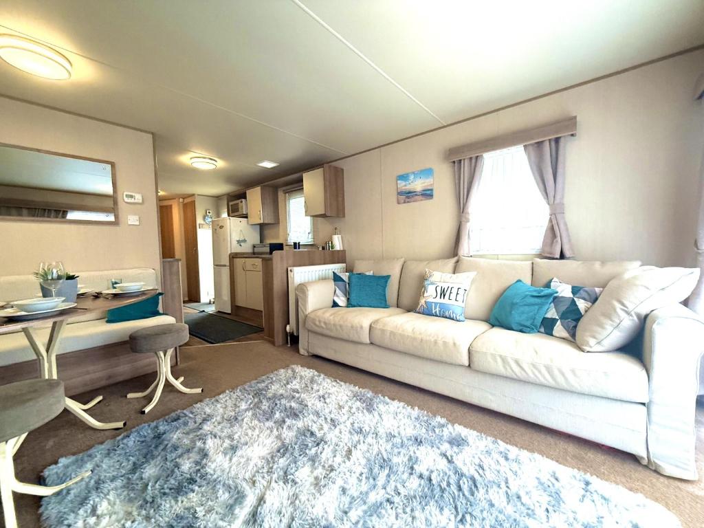 een woonkamer met een witte bank en een tafel bij Paddy's Place in Filey